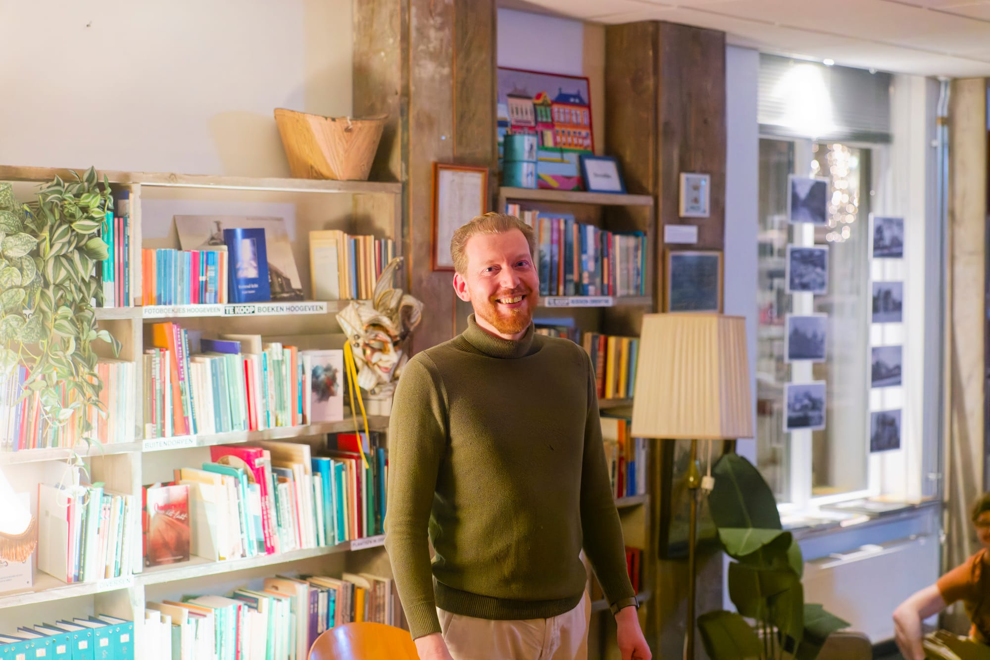 Floris van Lint hosting Het Hooge Woord in front of bookshelves and audience space
